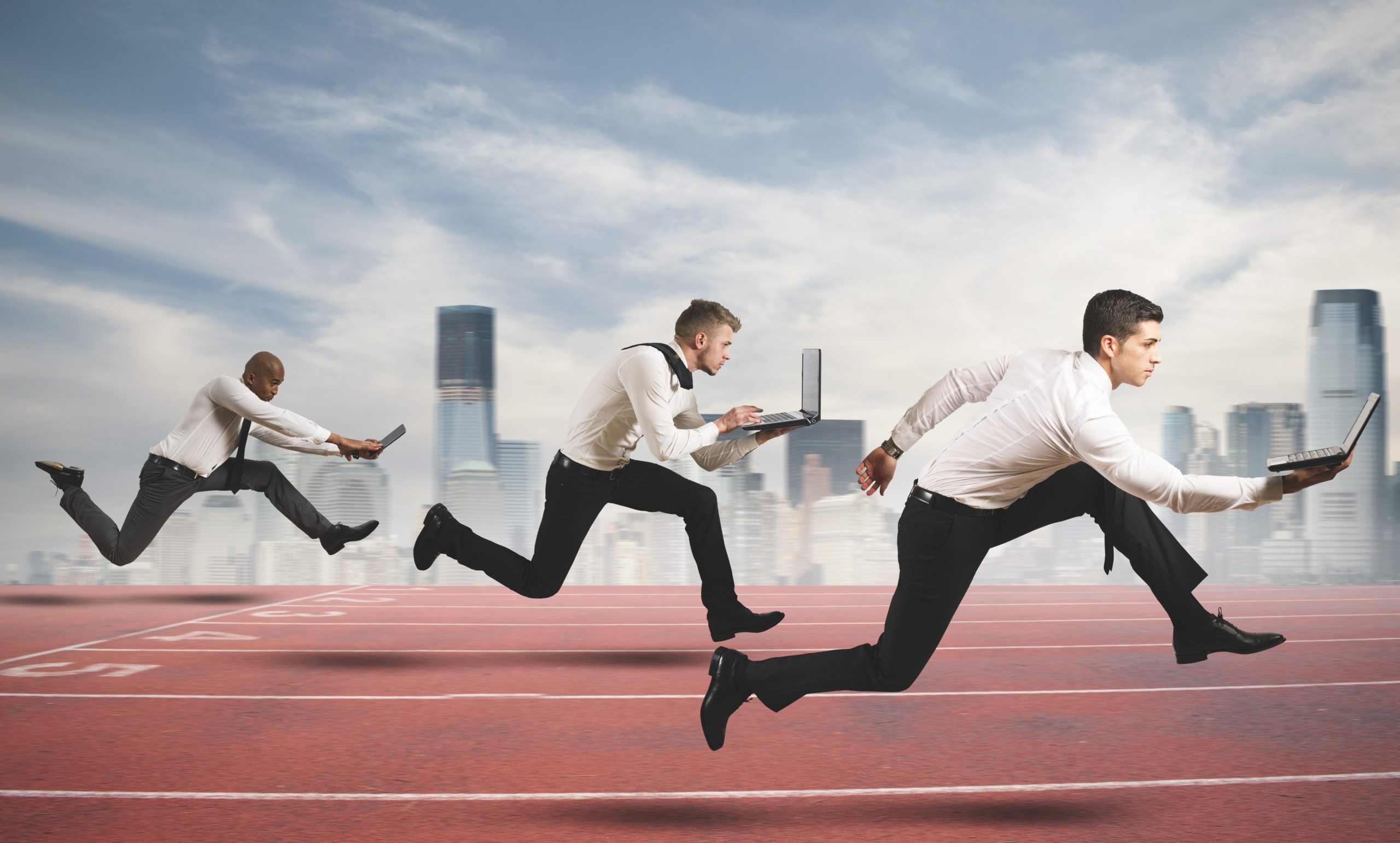 Three businessmen wearing suits running on track with laptops, racing to find out how to speed up your computer.